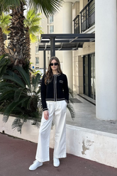 a lady in a black knit top and a pair of white pants